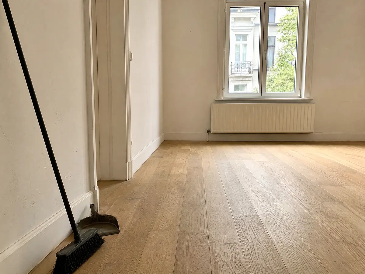 Swept wooden floor with a broom against the skirting board in an empty room after a clearance